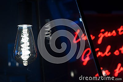 Edison lightbulb with red neon letters in the background Stock Photo