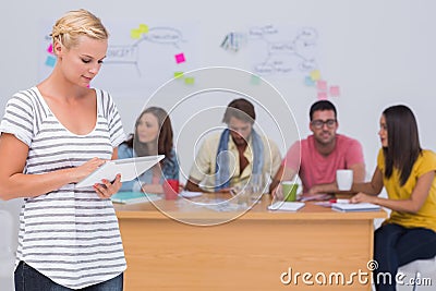 Editor using tablet pc as team works behind her Stock Photo