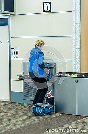 A traveler is filling an empty water container after security check Editorial Stock Photo