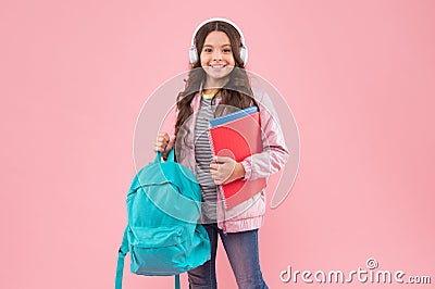 Educating ear to music. Happy kid wear earphones. Music education. Little girl hold books and bag. Musical notation Stock Photo