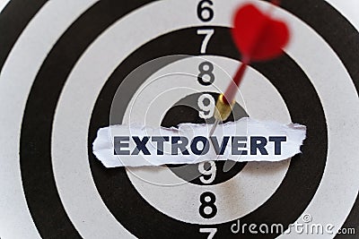 A piece of paper with the text is nailed to the target with a dart - EXTROVERT Stock Photo