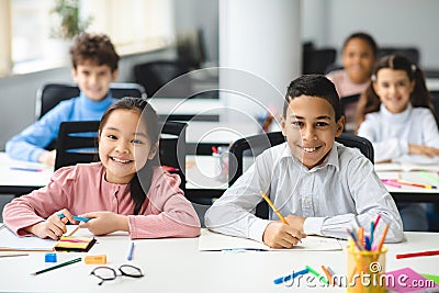 Portrait of small girl and boy sitting at desk in classroom Stock Photo