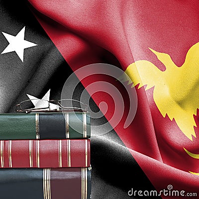 Education concept - Stack of books and reading glasses against National flag of Papua New Guinea Stock Photo