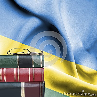 Education concept - Stack of books and reading glasses against National flag of Rwanda Stock Photo