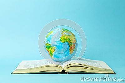Education and globalism concept. Globe on an open book on a table in a university class on a blue background Stock Photo