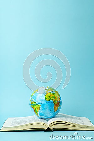 Education and globalism concept. Globe on an open book on a table in a university class on a blue background Stock Photo