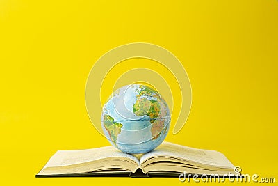 Education and globalism concept. Globe on an open book on a table in a university class on a yellow background Stock Photo
