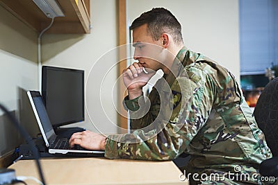 Education, the most powerful tool there is. a young soldier using a laptop in the dorms of a military academy. Stock Photo