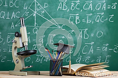 Education and sciences concept - books on the teacher desk in the auditorium, chalkboard on the background Stock Photo