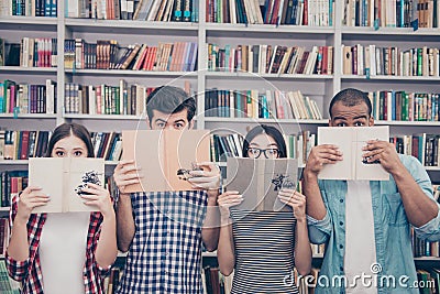 Education and teenage concept. Group of four muiti ethnic students in casual outfits are hiding behind the open books, with wide Stock Photo