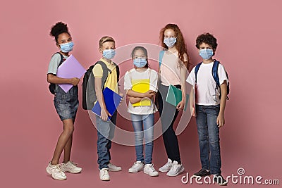Education during virus outbreak. Diverse children with schoolbags and notebooks wearing masks on pink background Stock Photo