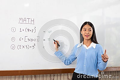 Educational concept a young smart female teacher explaining decision of hard math in a classroom before Covid-19 epidemic Stock Photo