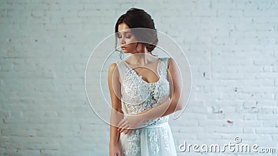 Een mooie dame met donker haar in een zacht kapsel bevindt zich in de studio in een lange elegante witte kleding, het stellen stock video Een mooie dame met donker haar in een zacht kapsel bevindt zich in de studio in een lange elegante witte kleding, het stellen stock video