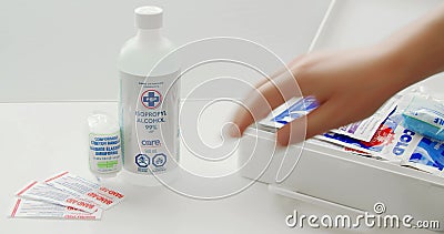 Een persoon die EHBO-artikelen verpakt naast een fles met isopropylalcohol voor gebruik in een witte tafel stock videobeelden Een persoon die EHBO-artikelen verpakt naast een fles met isopropylalcohol voor gebruik in een witte tafel stock videobeelden