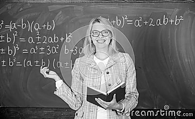 Effective teaching involve acquiring relevant knowledge. Woman teaching near chalkboard in classroom. Effective teaching Stock Photo