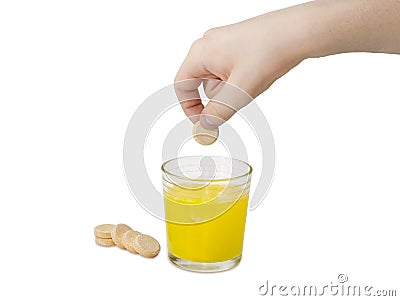 Effervescent medicinal tablet in hand over a glass of solution Stock Photo