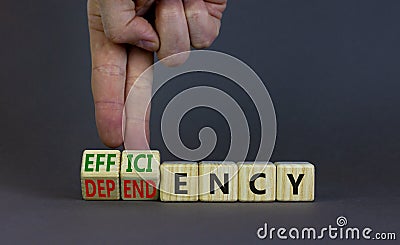 Efficiency or dependency symbol. Businessman turns cubes, changes the word dependency to efficiency. Beautiful grey table, grey Stock Photo
