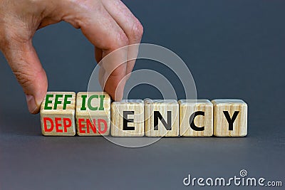 Efficiency or dependency symbol. Businessman turns cubes, changes the word dependency to efficiency. Beautiful grey table, grey Stock Photo