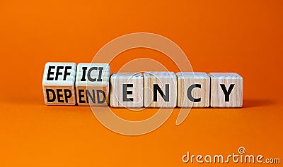Efficiency or dependency symbol. Turned wooden cubes and changed the word dependency to efficiency. Beautiful orange table, orange Stock Photo