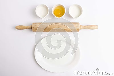 Egg, flour, milk, wooden rolling pin and white plate on white background Stock Photo