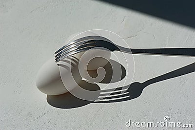 Egg with shadow from the fork.Minimalism. Cooking pastries, omelets. Easy. Shadows and light. Stock Photo