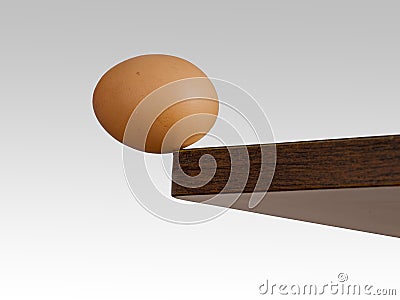 Egg teetering on the edge. Brink. Stock Photo