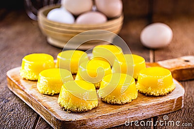Egg yolk candy, called Quindim in Brazil, and Portugal in brisa-do-Lis. Sweet dessert on rustic wooden background Stock Photo