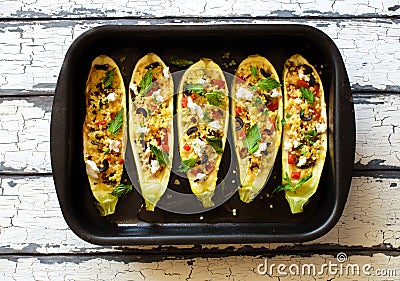 Eggplants stuffed with couscous, vegetables, soft cheese and olives on black baking sheet Stock Photo