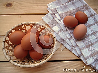 Eggs in the basket and on the kitchen towel on a wooden table, rustic styl Stock Photo