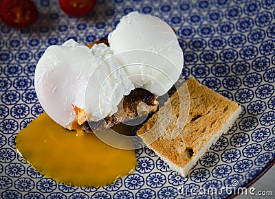 Eggs Benedict with meat steak, tomatoes and toast lying on a blue plate Stock Photo