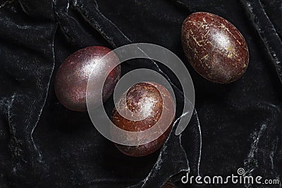Eggs stained with wine and covered with mother-of-pearl on a dark velvet background. Easter concept. Stock Photo