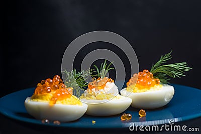 Eggs stuffed with red caviar tasty and healthy serving as in a restaurant on a blue plate Stock Photo