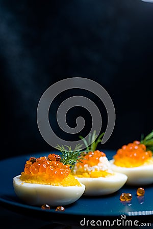 Eggs stuffed with red caviar tasty and healthy serving as in a restaurant on a blue plate Stock Photo