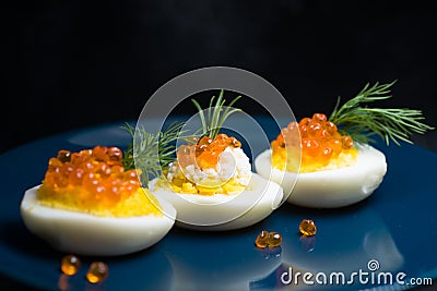 Eggs stuffed with red caviar tasty and healthy serving as in a restaurant on a blue plate Stock Photo