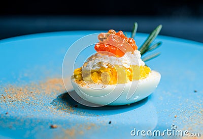 Eggs stuffed with red caviar tasty and healthy serving as in a restaurant on a blue plate Stock Photo