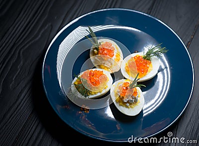 Eggs stuffed with red caviar tasty and healthy serving as in a restaurant on a blue plate Stock Photo