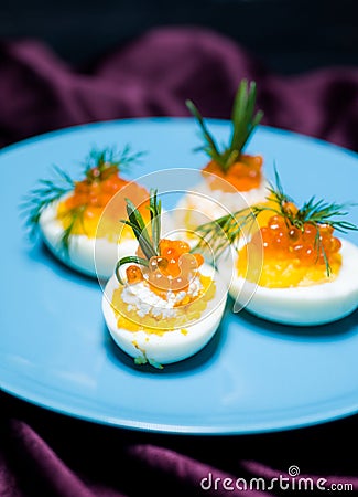 Eggs stuffed with red caviar tasty and healthy serving as in a restaurant on a blue plate Stock Photo