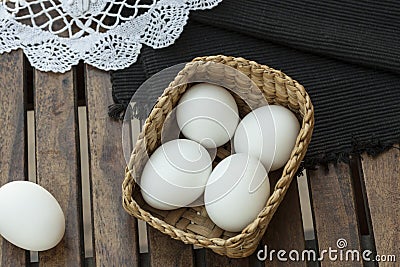 Eggs in a wooden basket which is isolated on wooden table. Stock Photo
