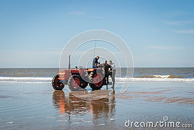 Egmond-aan-Zee, Netherlands - 2016-04-10: 3 men of the organisation with a red tractor on the beach Editorial Stock Photo