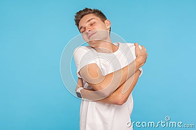 Ego and high self-esteem. Portrait of happy and selfish man in t-shirt embracing himself with expression of pleasure Stock Photo