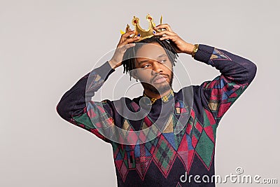 Egocentric self confident african man with dreadlocks trying on crown on his head, imagining himself king, leadership Stock Photo