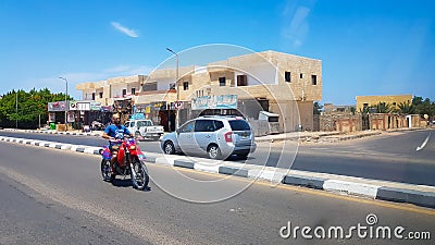 Egypt, Dahab - June 20, 2019: an Arab riding a scooter along one of the streets of Dahab. Desert Street. Egyptian residential Editorial Stock Photo