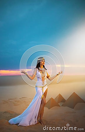 Egypt Woman pagan prays hands raised to heaven blue sky. Sexy girl Egyptian goddess Queen Cleopatra. yellow sand Sahara Stock Photo