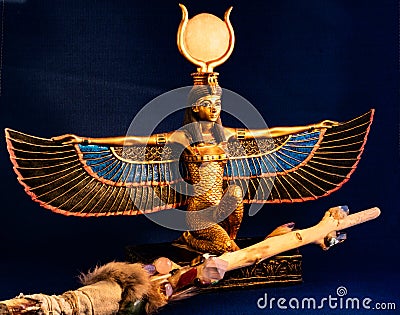 Egyptian goddess Isis kneeling with traditional magic wand made with quartz, amethyst crystals, wood and feathers Stock Photo