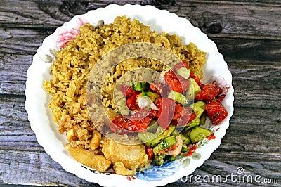 Egyptian rice cooked on hot steam, green salad and fried squid, a mollusc with an elongated soft body, large eyes, eight arms, and Stock Photo