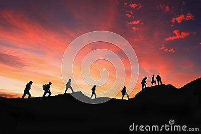 Eight friends walk on mountain path in sunset Stock Photo