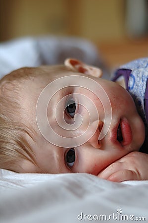 Eight month old sick baby lying in bed Stock Photo