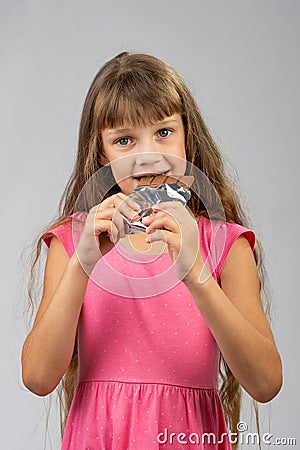 Eight-year-old girl eats chocolate bar Stock Photo