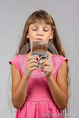 Eight-year-old girl with pleasure eats chocolate bar Stock Photo