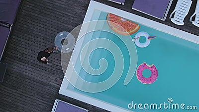 Eine Draufsicht des Pools mit mehrfarbigen aufblasbaren Kreisen und Sonne chairses, die das Pool bereitstehen Schießen von stock footage Eine Draufsicht des Pools mit mehrfarbigen aufblasbaren Kreisen und Sonne chairses, die das Pool bereitstehen Schießen von stock footage